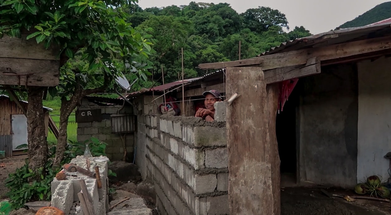 filipino man building wall and smiling