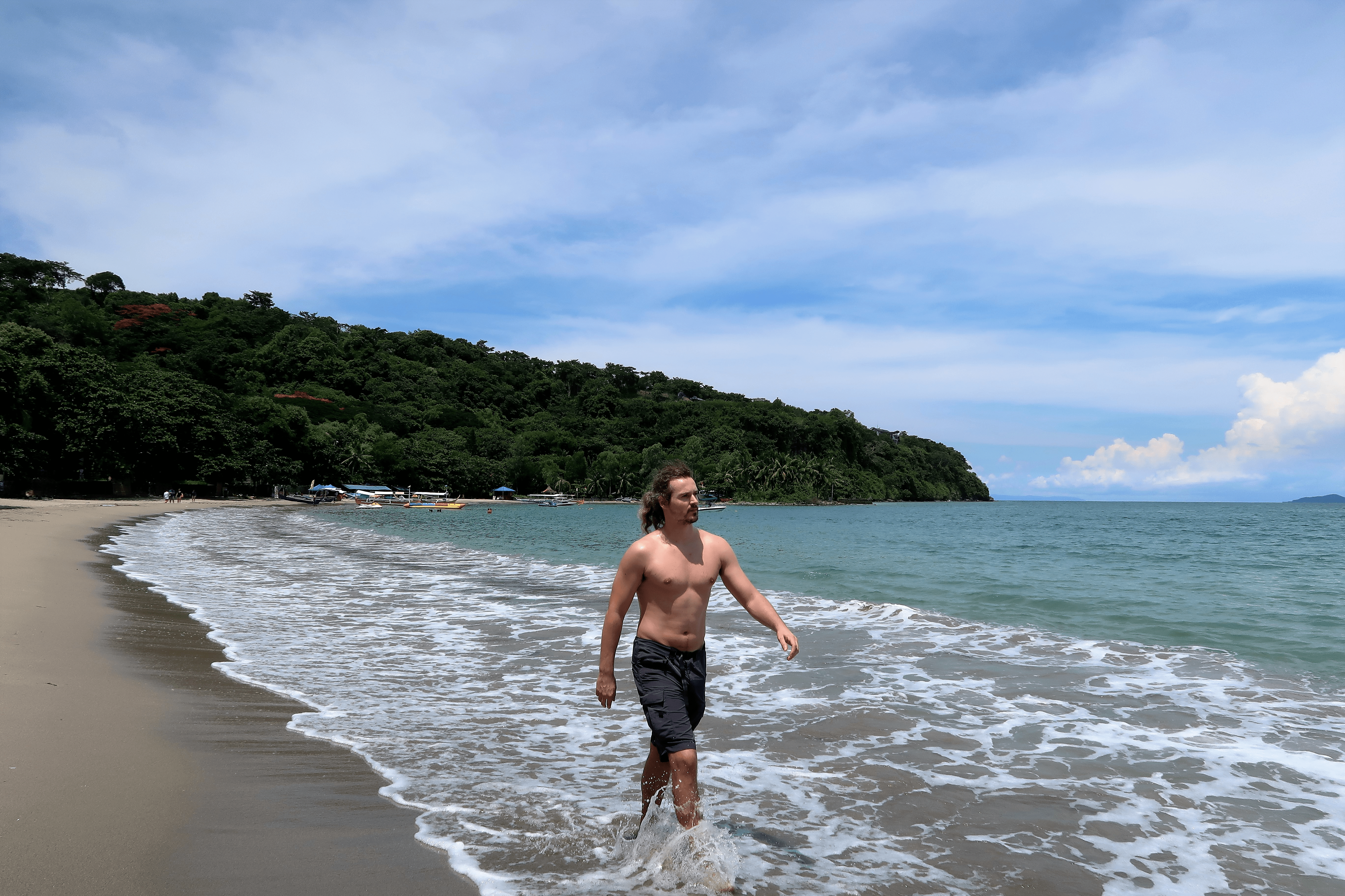 handsome man walking through the shore at the beach in the Philippines