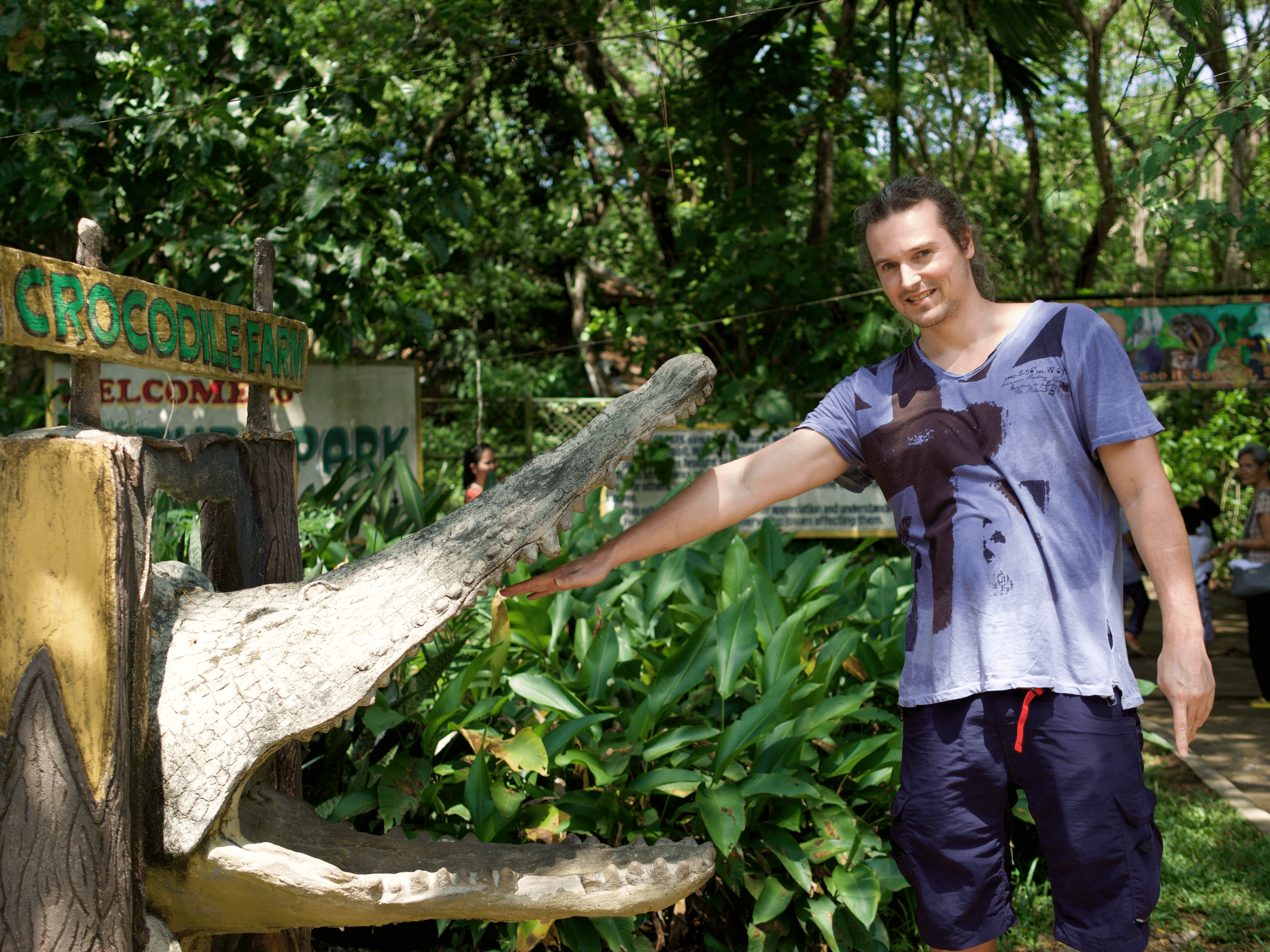 LennyThroughParadise sticking his hand in the mouth of a crocodile posing